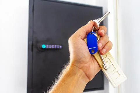 Hand holding keys from pin code box on hotel lobby wall Thailand. Stock-Fotos