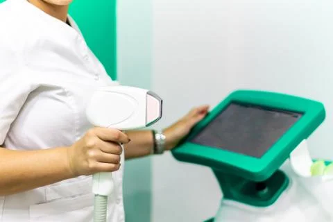 Hand holding laser depilation machine in clinic with white coat, clinical las Stock Photos