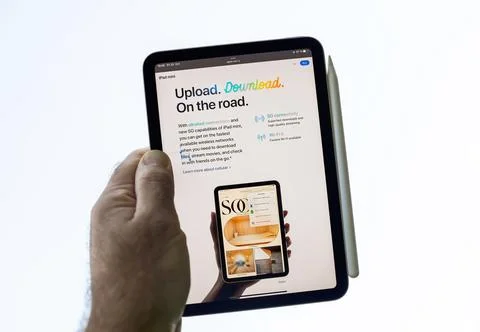 Hand holding latest iPad mini Pro tablet against white clear sky Stock Photos