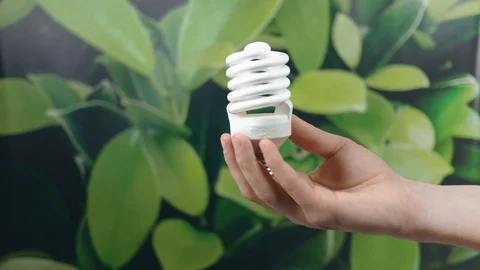 Hand holding LED Bulb with Lighting on green nature background. Eco power sav Stock Footage 121584209