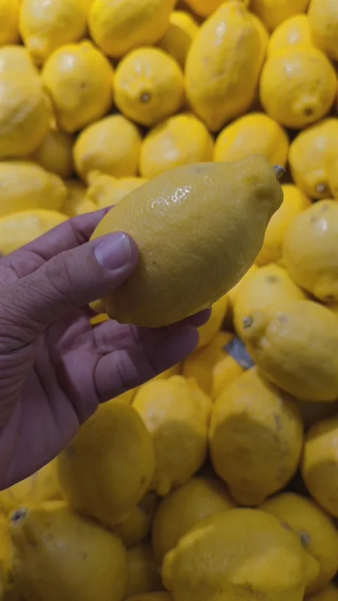 A hand holding Lemon while shopping in a supermarket Stock Footage 341554850