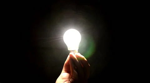 Hand holding a light bulb in the dark, the lamp lights up Video stock 57615896