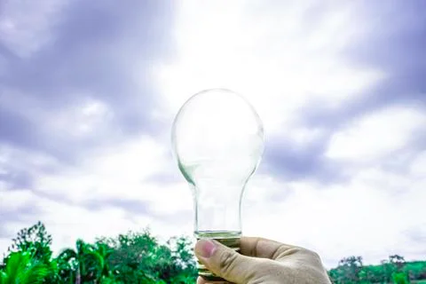 Hand holding light bulb with sunset sky, Use hand hold incandescent lamp for  Foto stock