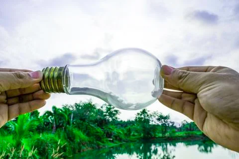 Hand holding light bulb with sunset sky, Use hand hold incandescent lamp for  Foto stock