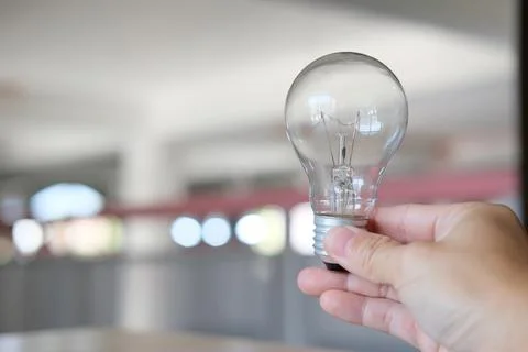 Hand holding a light bulb on a table notion of idea Stock Photos