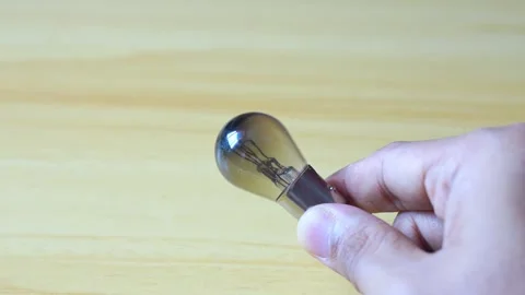 Hand holding light bulb on wood background Stock Footage 332591007