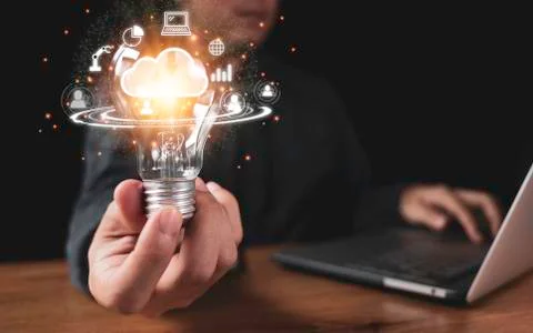 Hand holding lightbulb with cloud computing and technology icons Stock Photos