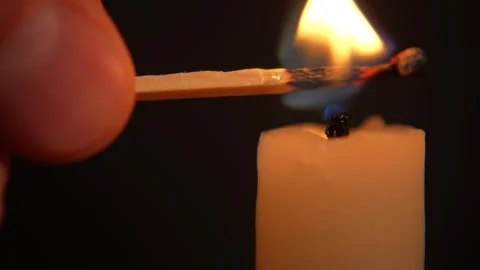 A hand holding a lighted match and lighting a white candle Stock Footage 320191730