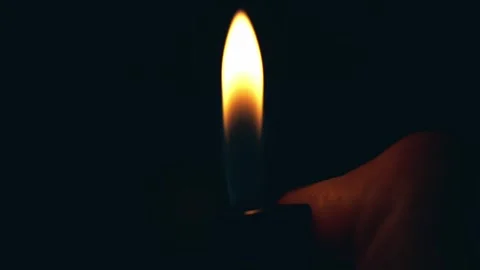 A hand holding a lighter, igniting a flame against a dark background Stock-Footage 305996192