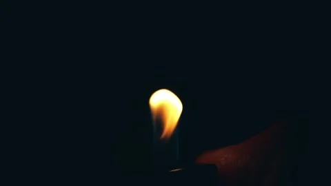 A hand holding a lighter, igniting a flame against a dark background Stock-Footage 305996201