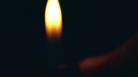 A hand holding a lighter, igniting a flame against a dark background Stock-Footage 305996202