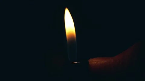 A hand holding a lighter, igniting a flame against a dark background Stock-Footage 305996206