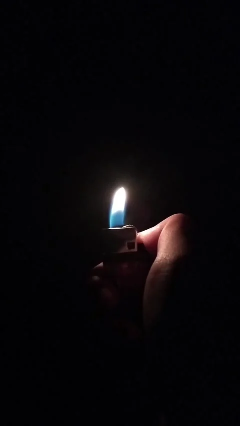 Hand holding a lit lighter in complete darkness Stock Footage 327585412