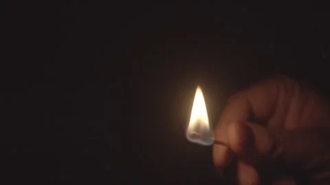 Hand Holding Lit Match Igniting Flame Against Dark Void Vídeos de archivo 334644127