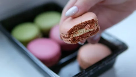 Hand holding macaron on nature background. A Macaron is a sweet meringue-based Stock Footage 302104751