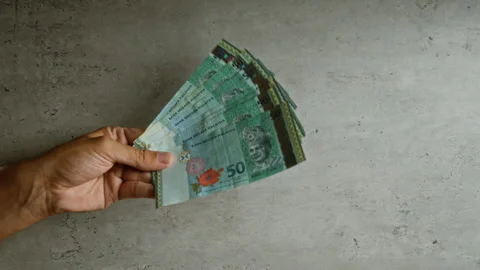 Hand holding malaysian ringgit banknotes against a concrete background, fea.. Stock-Footage 296031496