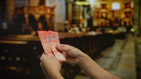 Hand holding malaysian ringgit indoors with blurred church interior suggest.. Stock-Footage 304952768