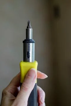 Hand holding manual multi bit screwdriver with steel shaft and yellow handl.. Stock Photos