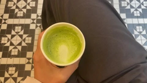 Hand holding matcha cup at the cafe Stock Footage 313629371