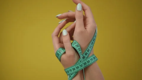 Hand Holding a Measuring Tape Set Against a Vibrant and EyeCatching Stock Footage 283573526