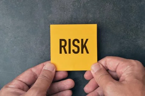 Hand holding a memo note written with text RISK. Stock Photos