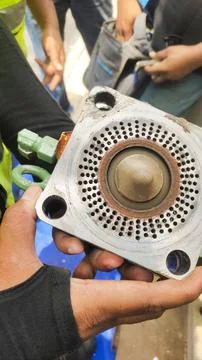 A hand holding a metallic component, likely part of a machinery or equipment. Stock Photos