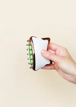 Hand holding a microcurrent massage device with therapeutic green light mode on Stock Photos