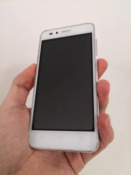 Hand holding a mid-range cheap white smartphone isolated on white background Stock Photos