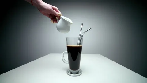 Hand holding milker and pouring milk into a coffee mug. Stock Footage 146987341