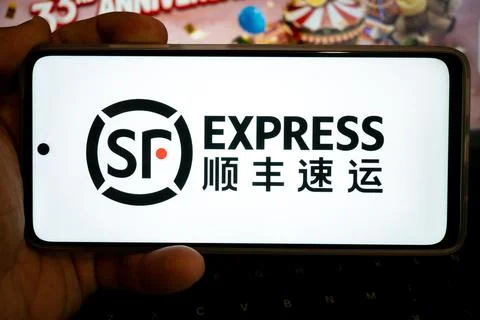 Hand holding mobile device displaying sf express logo 写真素材