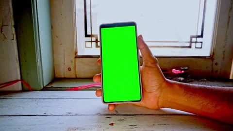 A hand holding a mobile phone with a bright green screen for chroma key com.. Stock Footage 345133924