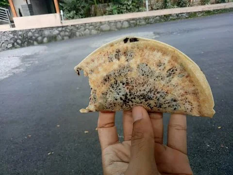 Hand holding moldy bread slice on street near plants Stock Photos