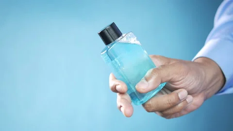 Hand holding mouthwash liquid container over blue background Stock Footage