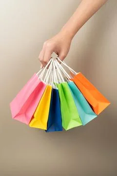 Hand holding multi colored gift or shopping bags isolated Stock Photos
