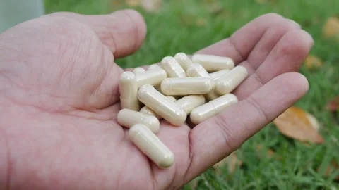 Hand holding multiple white herbal supplement capsules Vídeos de archivo 330764196