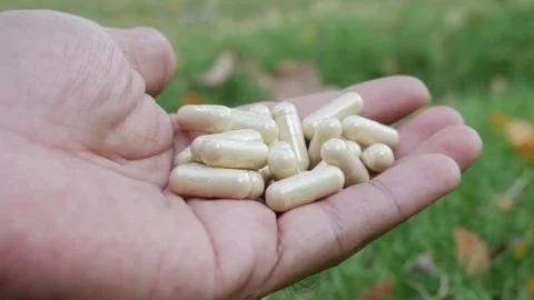 Hand holding multiple white herbal supplement capsules Stock Footage 333291959