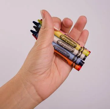 Hand holding new colorful crayons from Crayola Stock Photos