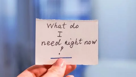 Hand holding note with question about needs in blurred background Stock Photos