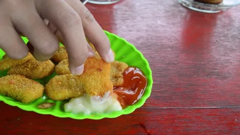 The hand holding the nugget. Delicious crispy breaded chicken nuggets. 스톡 동영상 259537093
