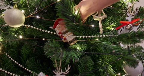 Hand holding nutcracker ornament decorating green Christmas tree with silver Video stock 322577067