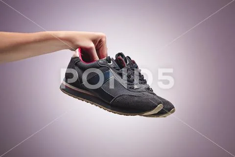 Hand Holding An Old Dirty Sneaker Shoe Stock Photos