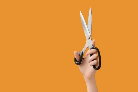 Hand holding open scissors with sharp blades and black handles on a solid ora Stock Photos