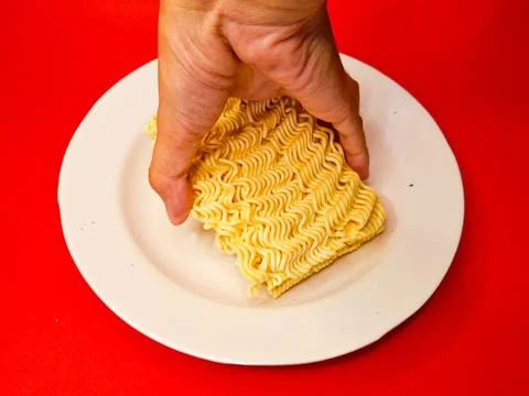 Hand holding or picking up raw dry noodles on a white plate, Dried Ramen Stock Photos