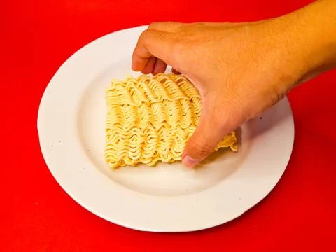 Hand holding or picking up raw dry noodles on a white plate, Dried Ramen Stock Photos