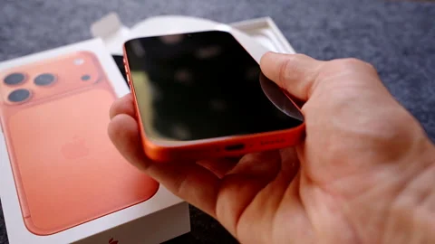 Hand Holding Orange iPhone 17 Pro Above Box with Focus on Dual Camera and Design Vídeo Stock 317696204