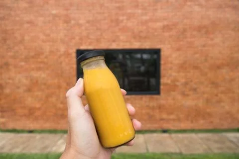 Hand holding orange juice in bottle blurred background Stock Photos