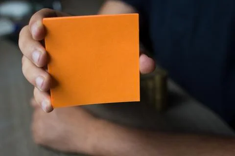 Hand holding an orange note paper - - Business Concept Stock Photos