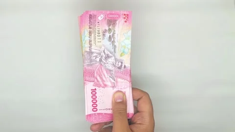 Hand holding out stack of Indonesian banknotes in the 100,000 denomination Video stock 302318956