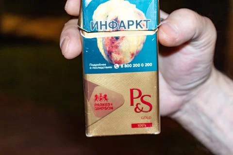 Hand holding a pack of cigarettes with a warning about heart attack Stock Photos