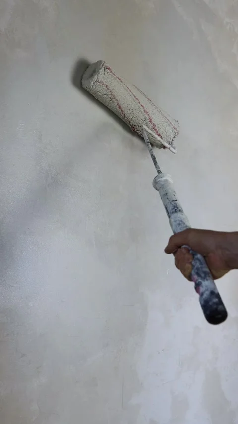 Hand holding a paint roller and applying fresh white paint on a concrete wall. Stock-Footage 287645516